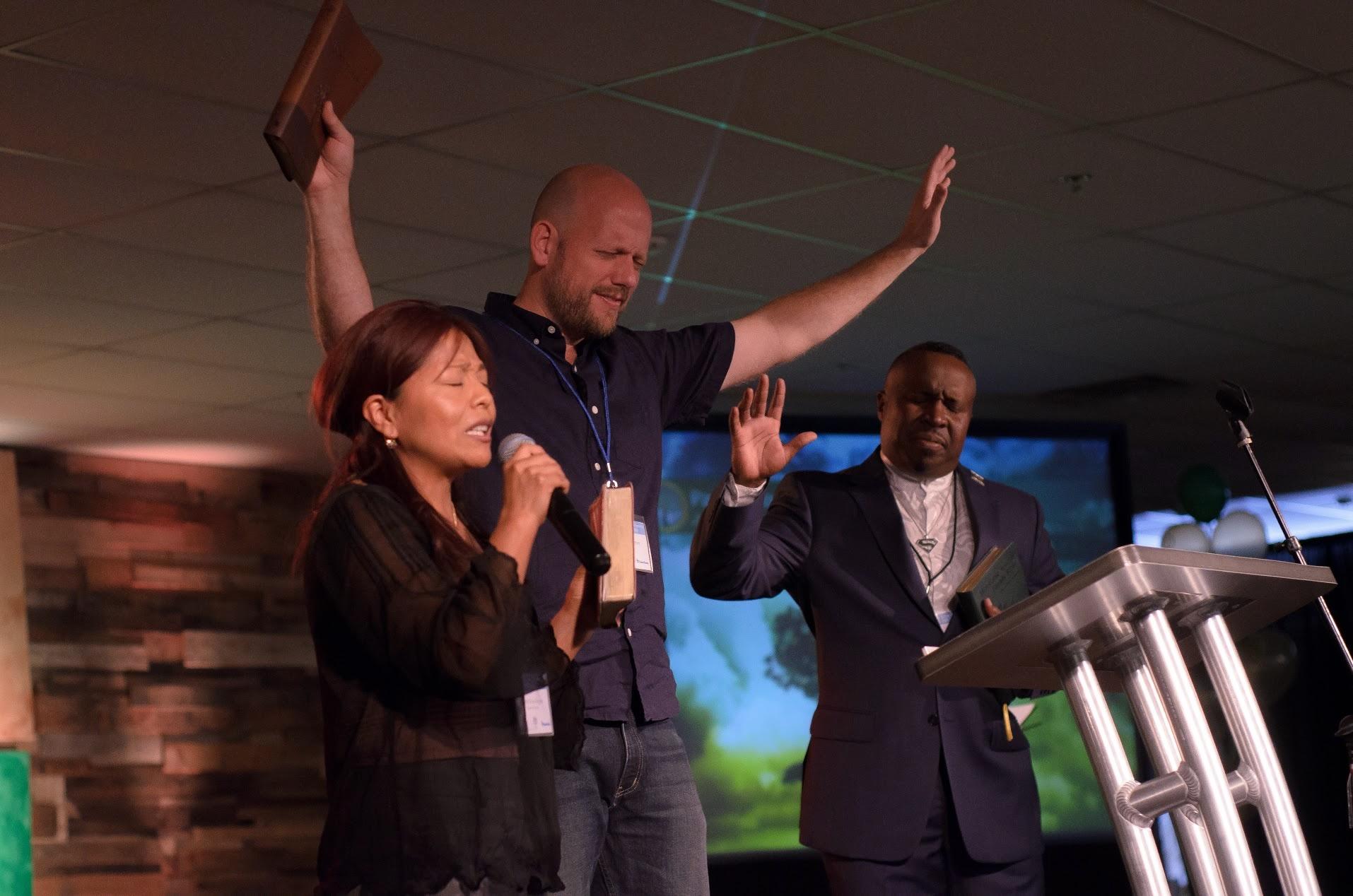 Jason and Norah Skipper praying on stage during a service at Journey Church in Rome, Georgia, alongside another pastor.