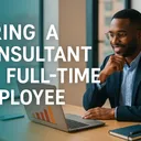 Professional man smiling while reviewing business graphs on a laptop, with text overlay 'HIRING A CONSULTANT VS. FULL-TIME EMPLOYEE'.